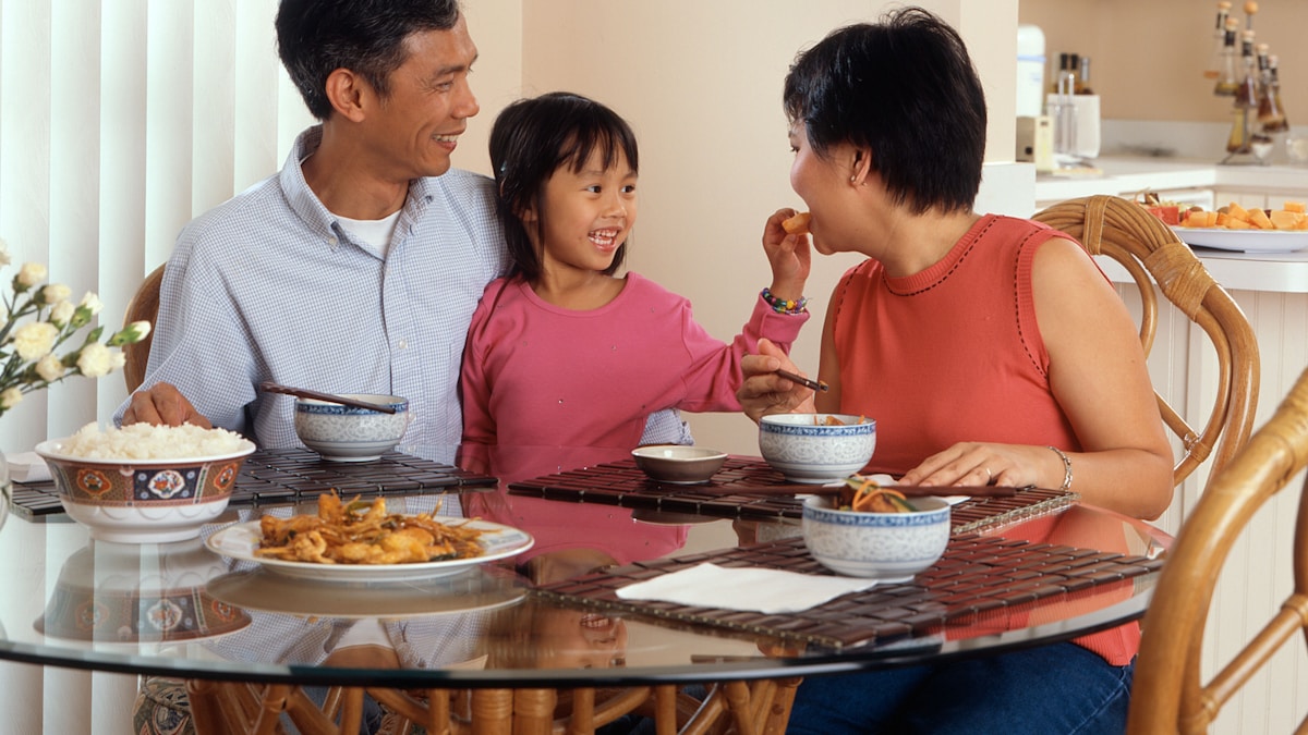 自宅の食卓で笑顔で食事をする家族